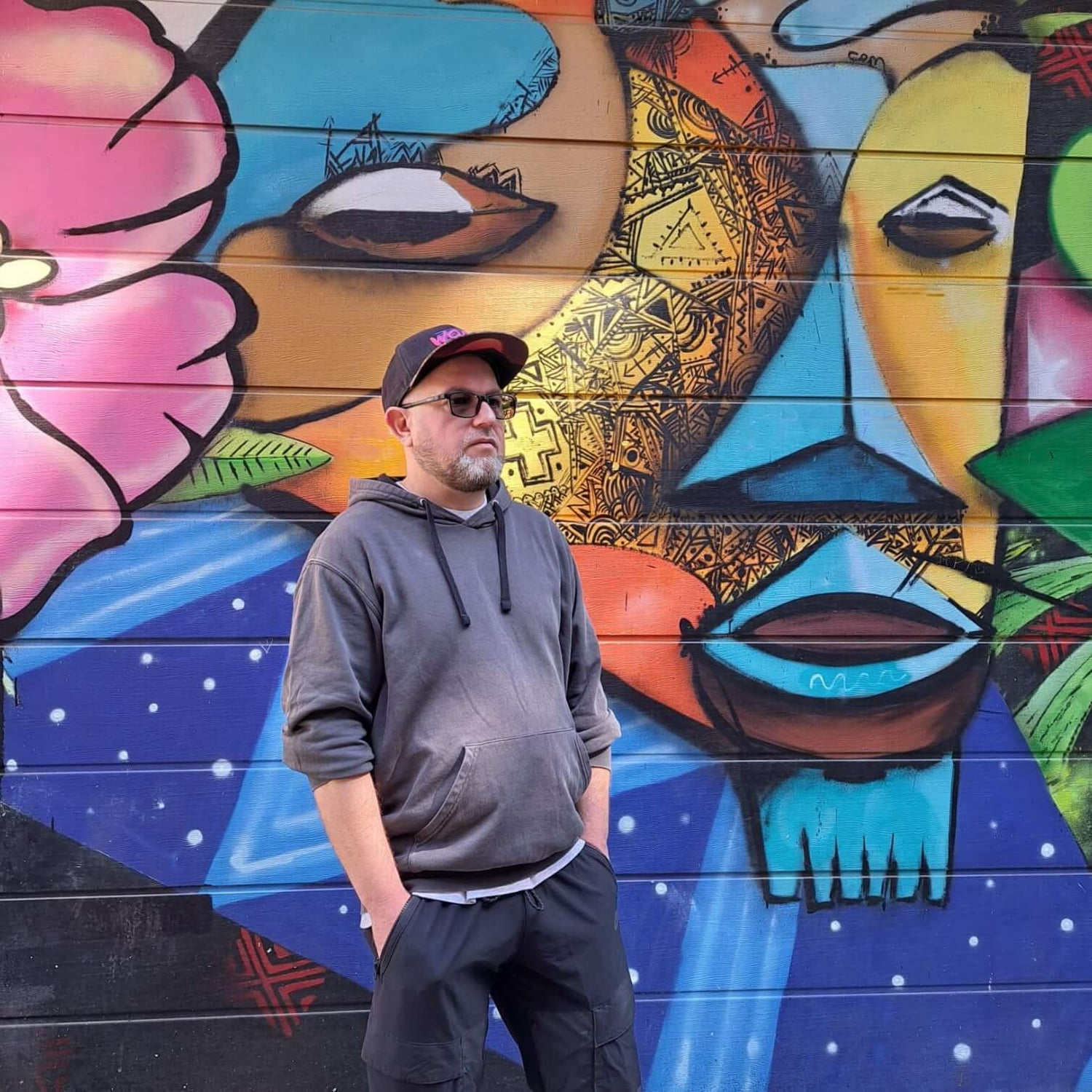 Cyril, le fondateur de Chollala devant une fresque aux motifs artistiques.