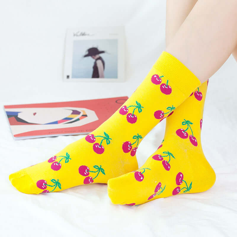 Chaussettes fantaisie jaunes vives décorées de cerises rouges et feuilles vertes, style fruité et pop pour un look coloré et original.